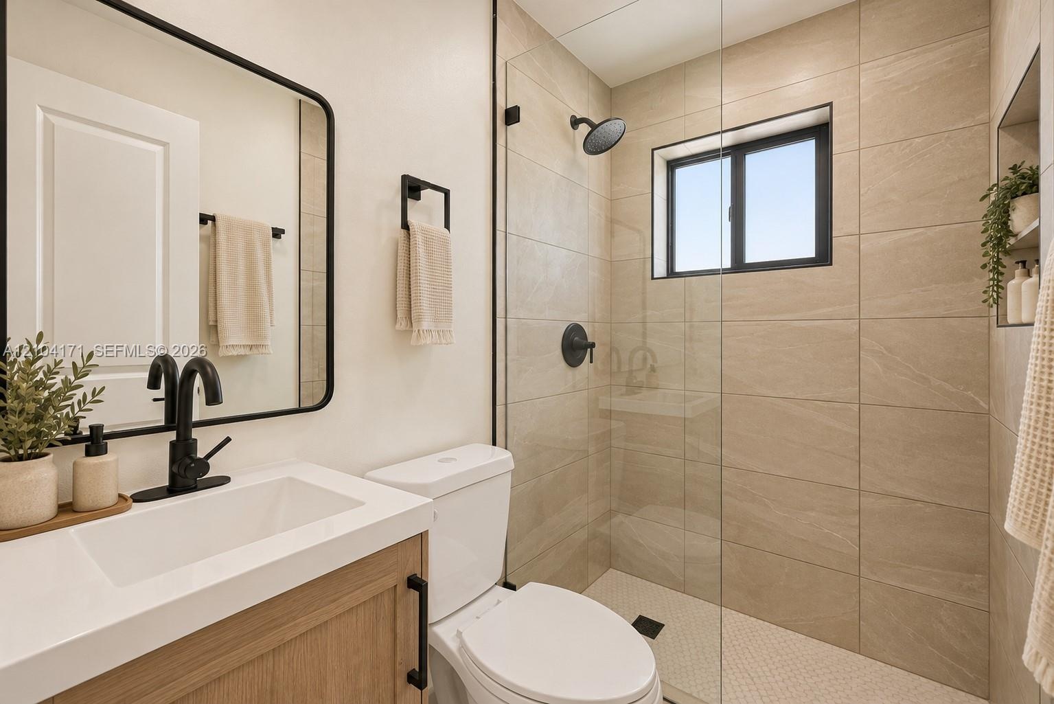 Bathroom featuring a wood-finish vanity with a white countertop, matte black hardware, a glass-enclosed shower with large-format tile surround, and a 
