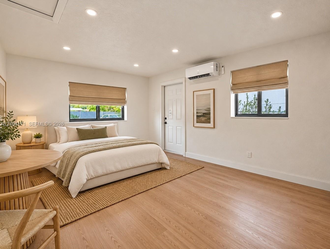 Wood-finish flooring, recessed lighting, dual windows with Roman shades, and a wall-mounted ductless mini-split system