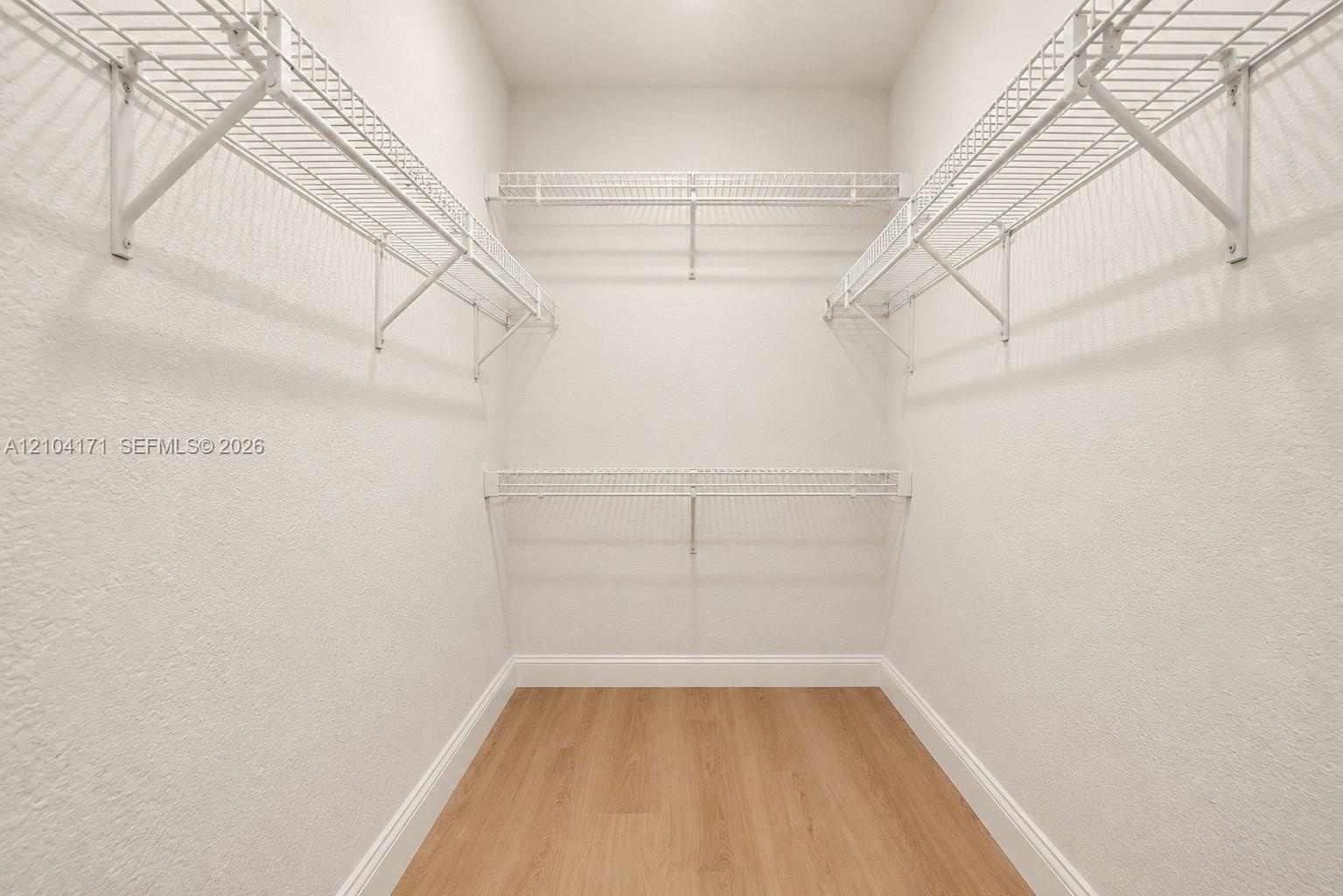 Walk-in storage space featuring wood-finish flooring and multi-level white wire shelving