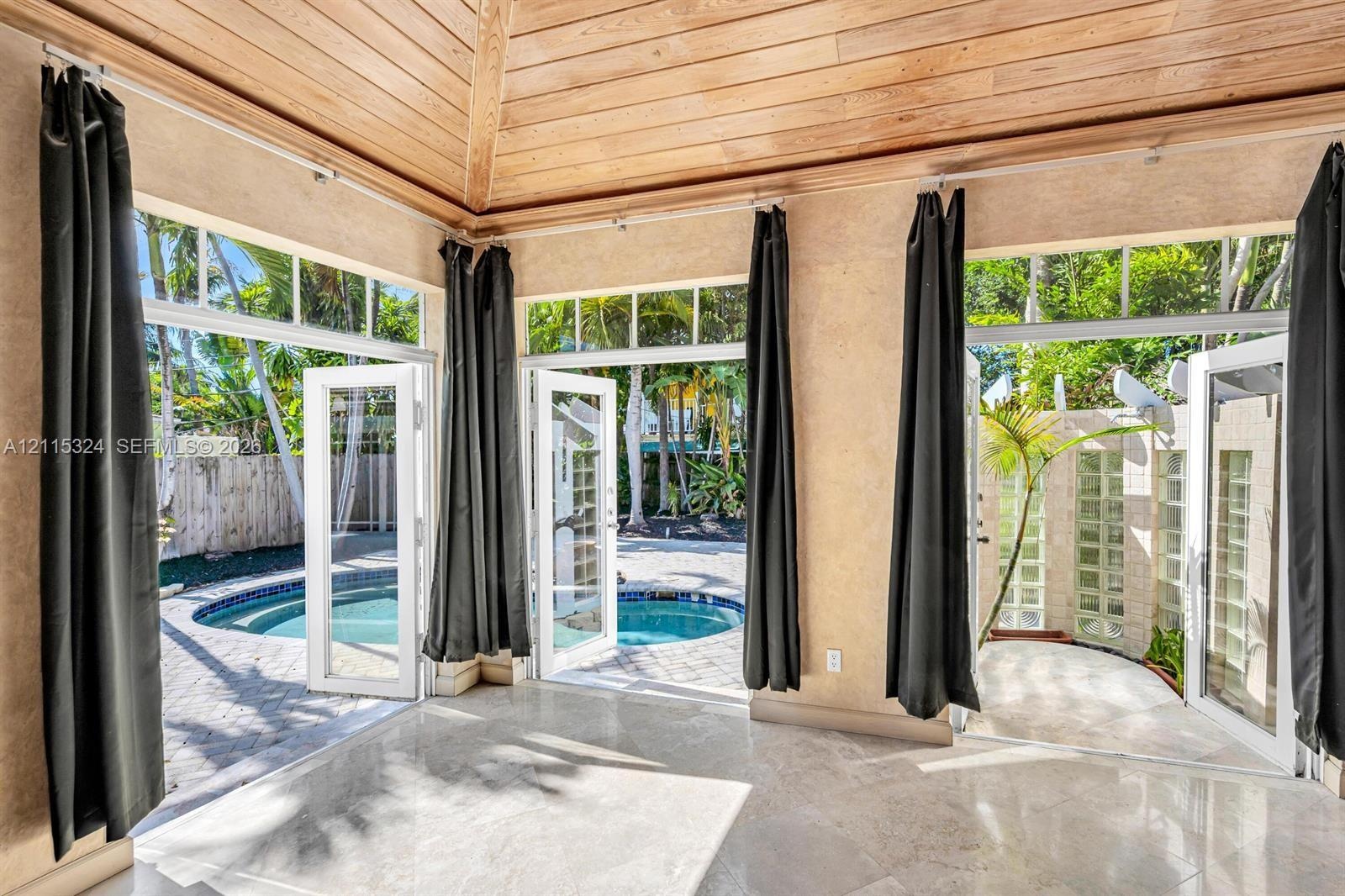 Sunroom featuring a vaulted wood-paneled ceiling, large-format tile flooring, and multiple glass-paned doors with transoms