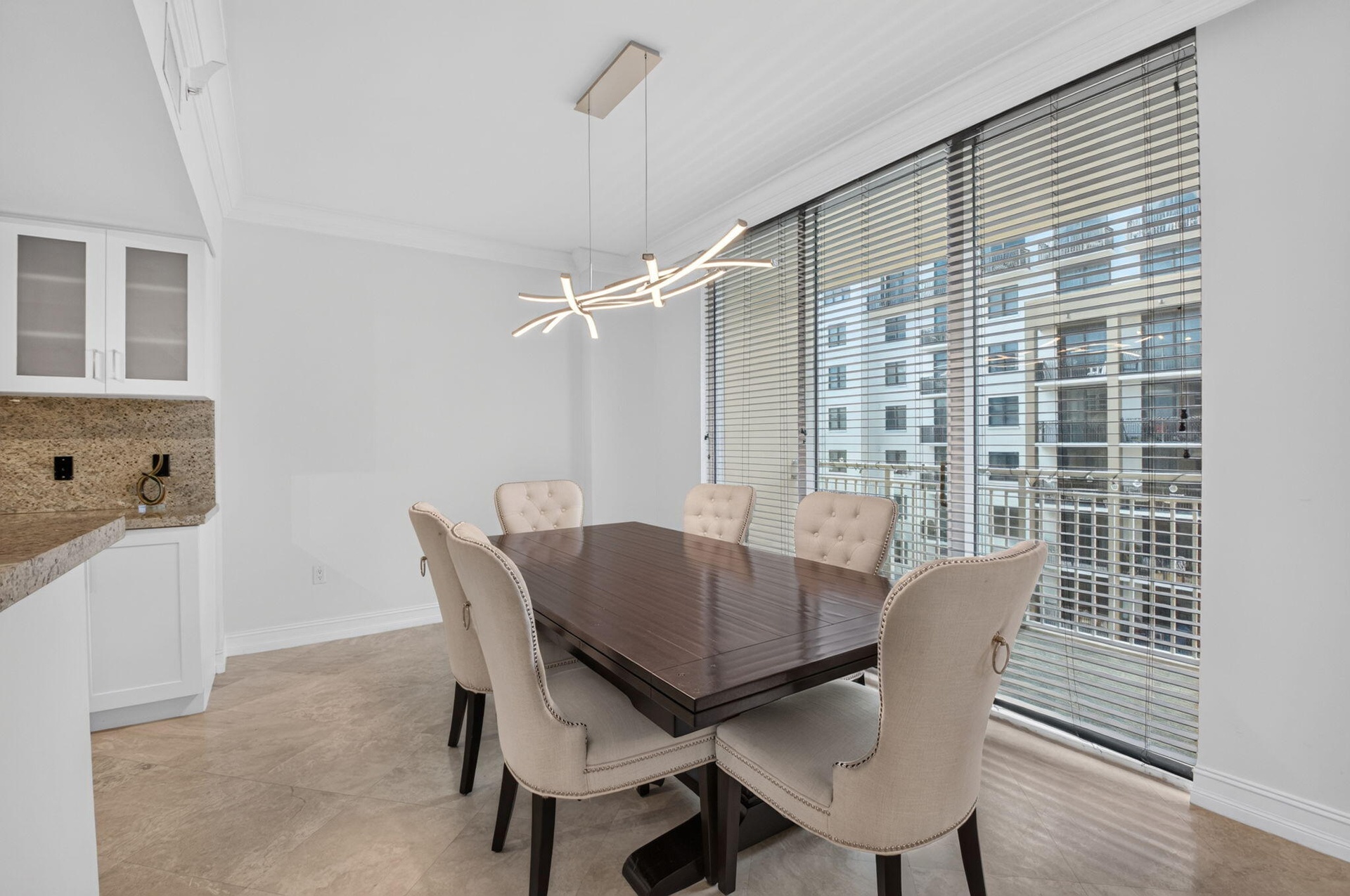 Contemporary chandelier illuminates the dining area with a view.
