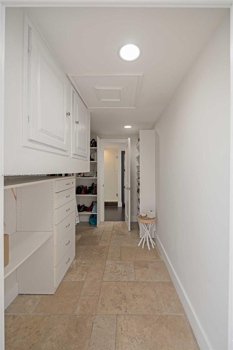 Storage area featuring stone-finish flooring, custom built-in white cabinetry, integrated drawer banks, and recessed lighting