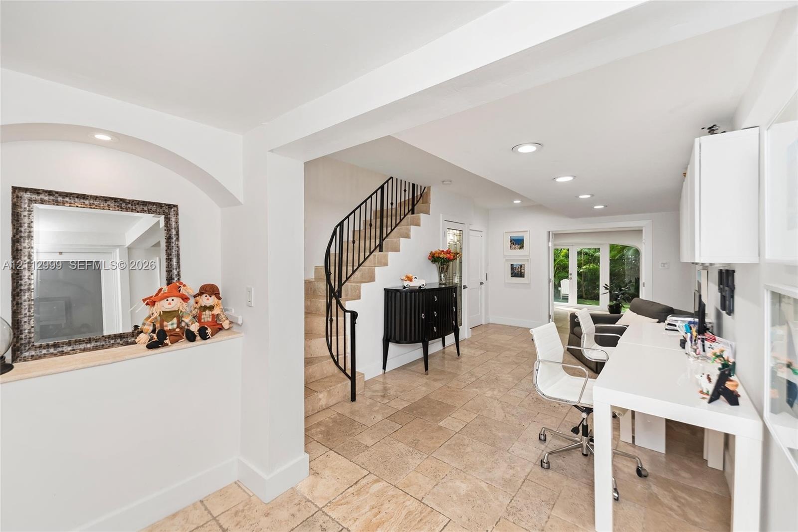 Interior space featuring stone-tile flooring, a curved staircase with metal railing, built-in wall niche with recessed lighting, and recessed ceiling 