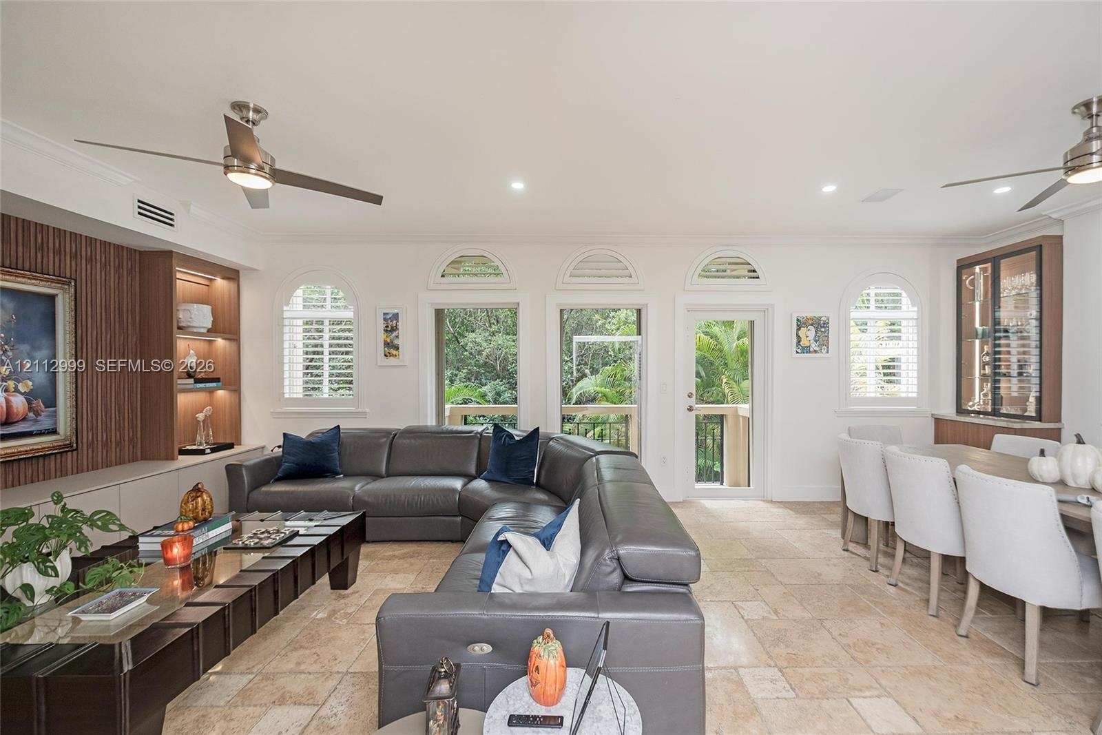 Open living space featuring stone flooring, arched windows, recessed lighting, built-in wooden display shelving, and dual ceiling fans
