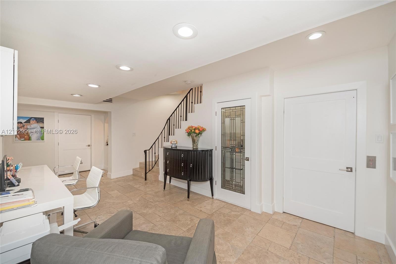 Tiled flooring, recessed lighting, staircase with metal railing, and glass-paneled interior door