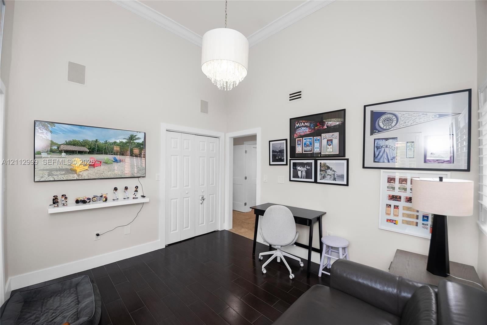 High vaulted ceilings featuring crown molding, dark wood-finish flooring, and a crystal drum chandelier