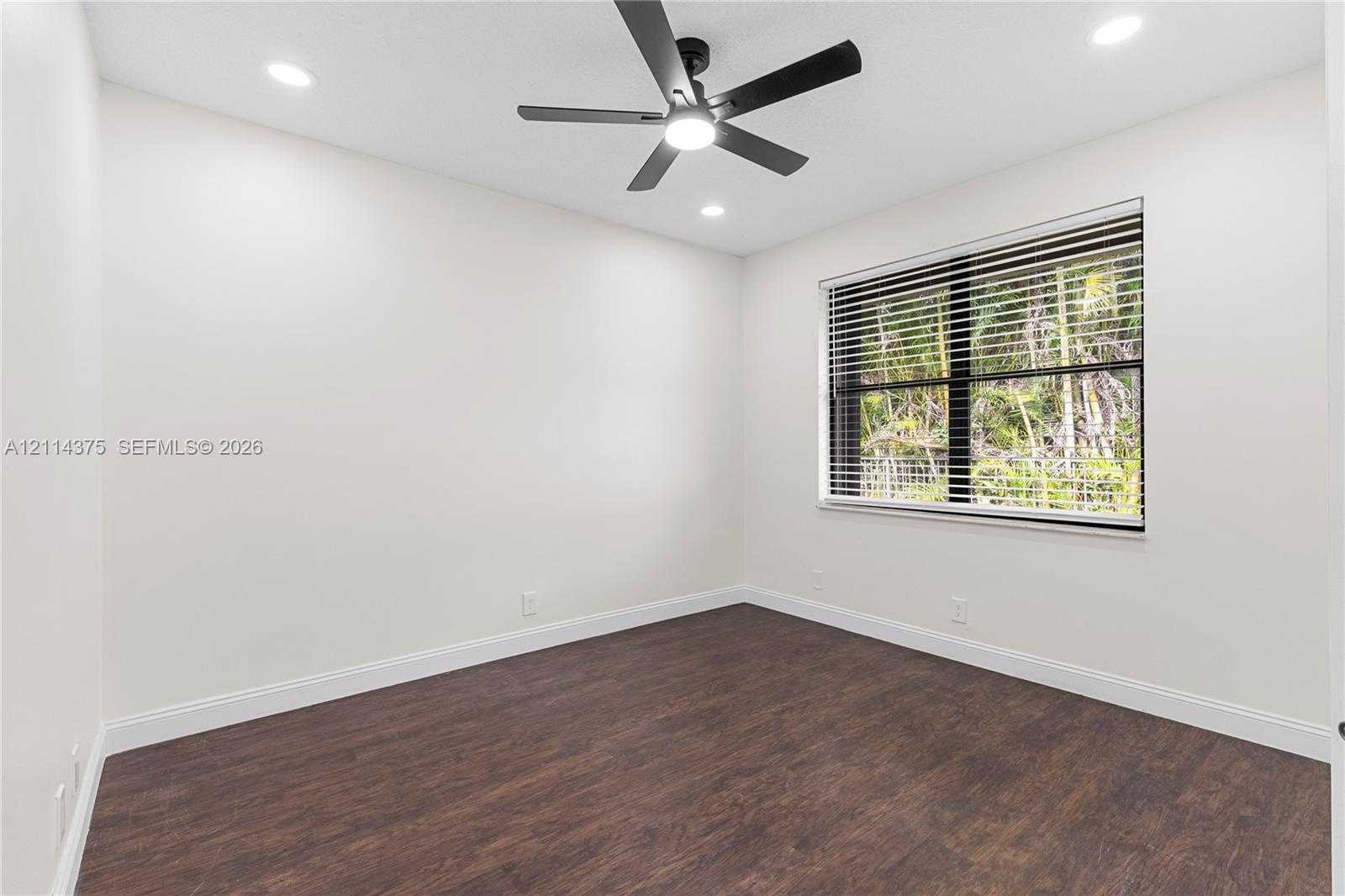 Room featuring wood-finish flooring, recessed lighting, and a multi-blade ceiling fan with integrated lighting