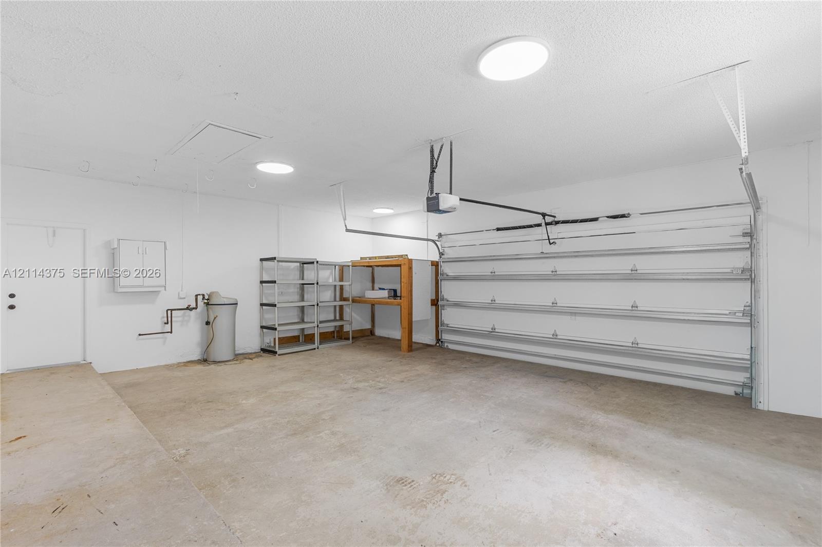 Multi-car garage featuring a concrete floor, automated sectional door, and flush-mount ceiling lighting