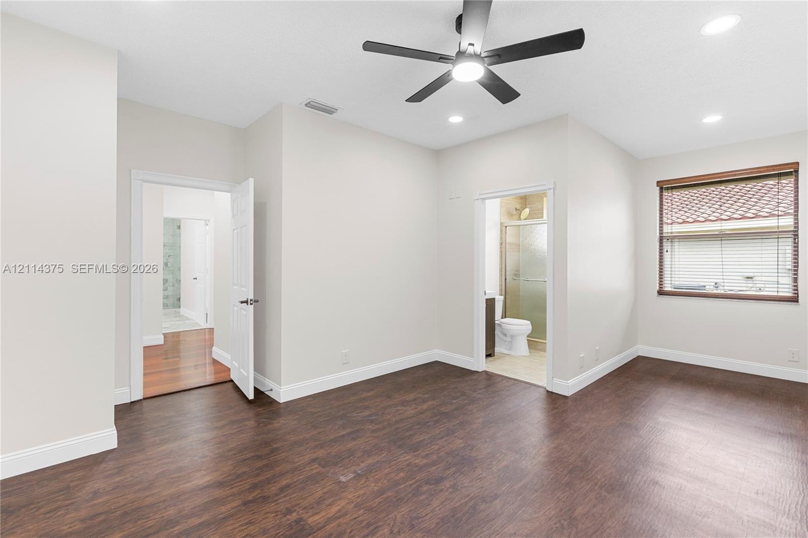 Interior space featuring wood-finish flooring, a multi-blade ceiling fan with integrated lighting, recessed lighting, and a window with horizontal bli