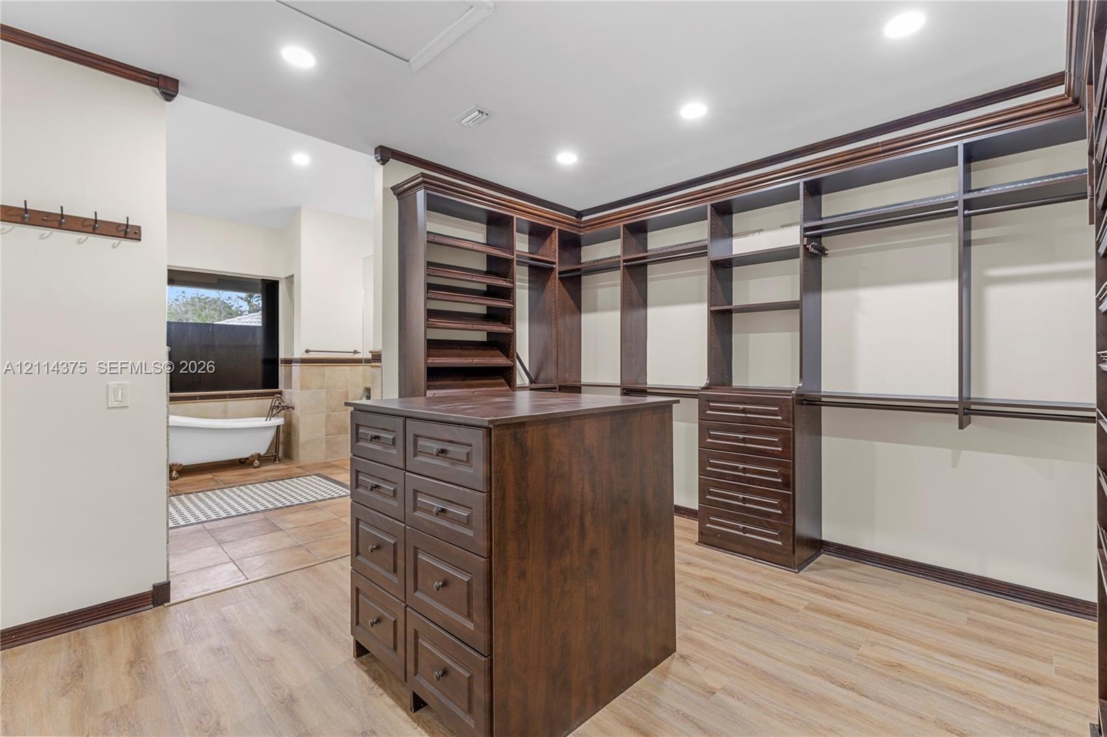 Custom dark wood cabinetry featuring floor-to-ceiling shelving, hanging rods, and a center island with built-in drawers