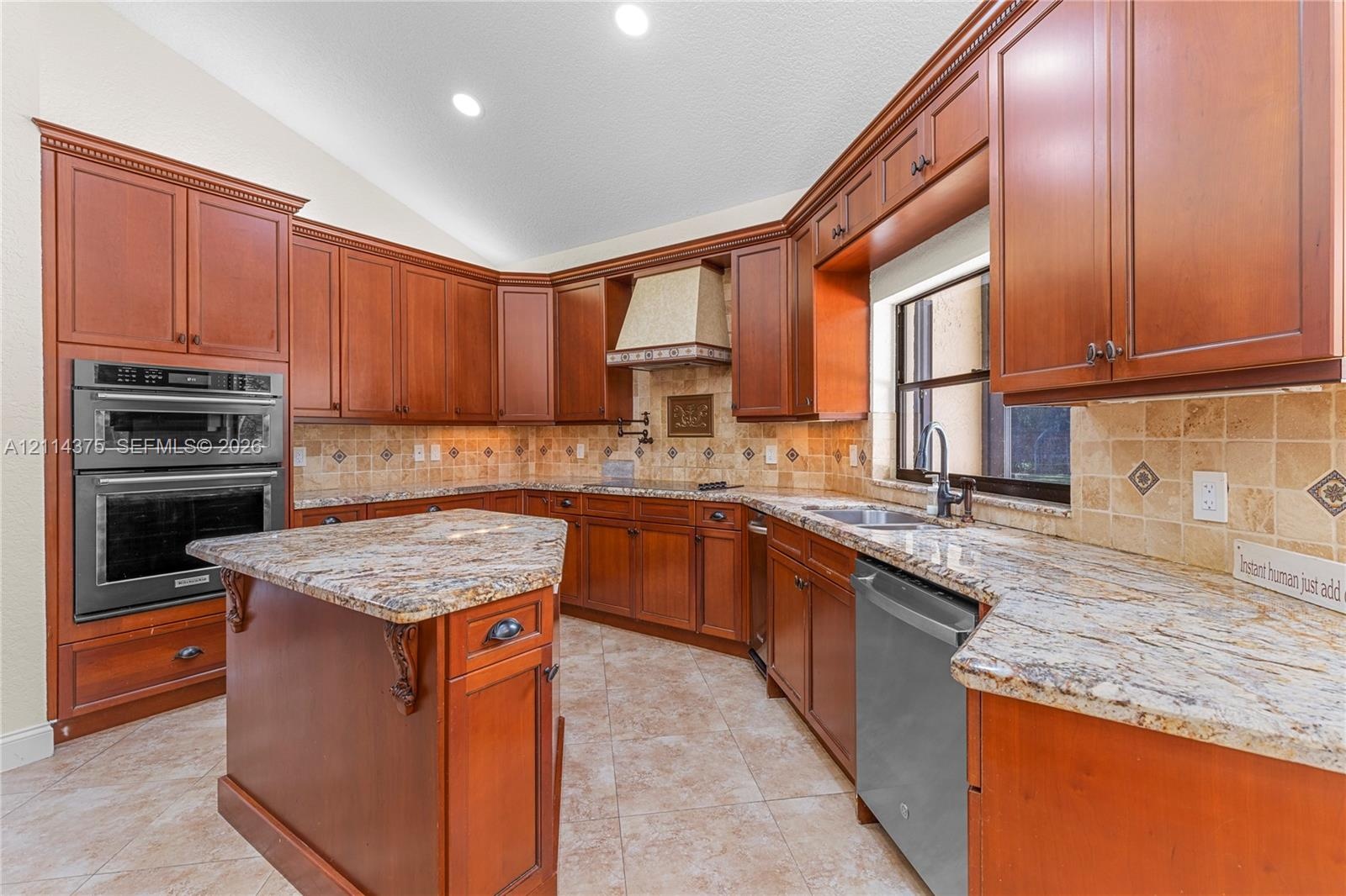 Kitchen featuring wood cabinetry, stone countertops, tiled backsplash, built-in double wall oven, and a center island