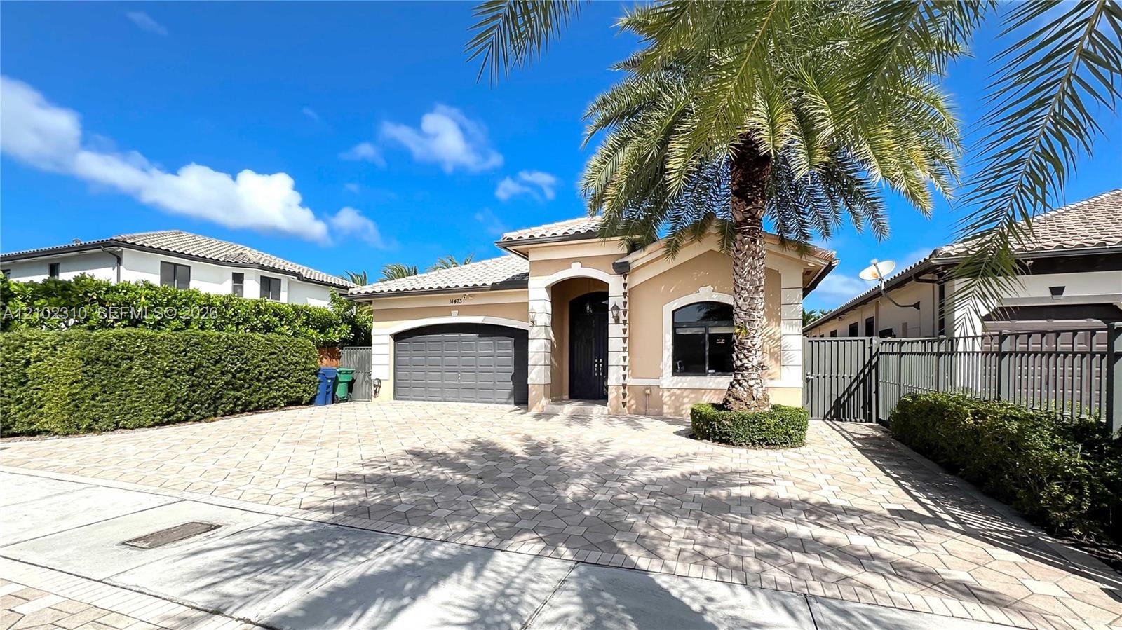 Single-story residence featuring a tile roof, stucco exterior, decorative stone trim, arched entryway, and a paver driveway