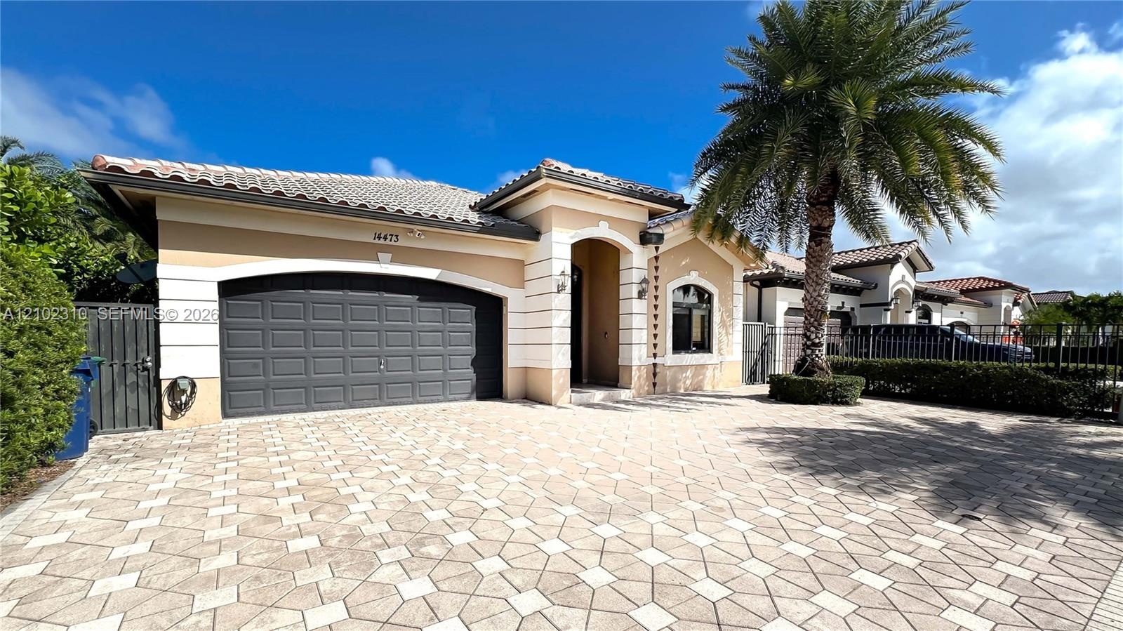 Stucco exterior featuring decorative quoins, arched entryway, tile roof, and a paved stone driveway