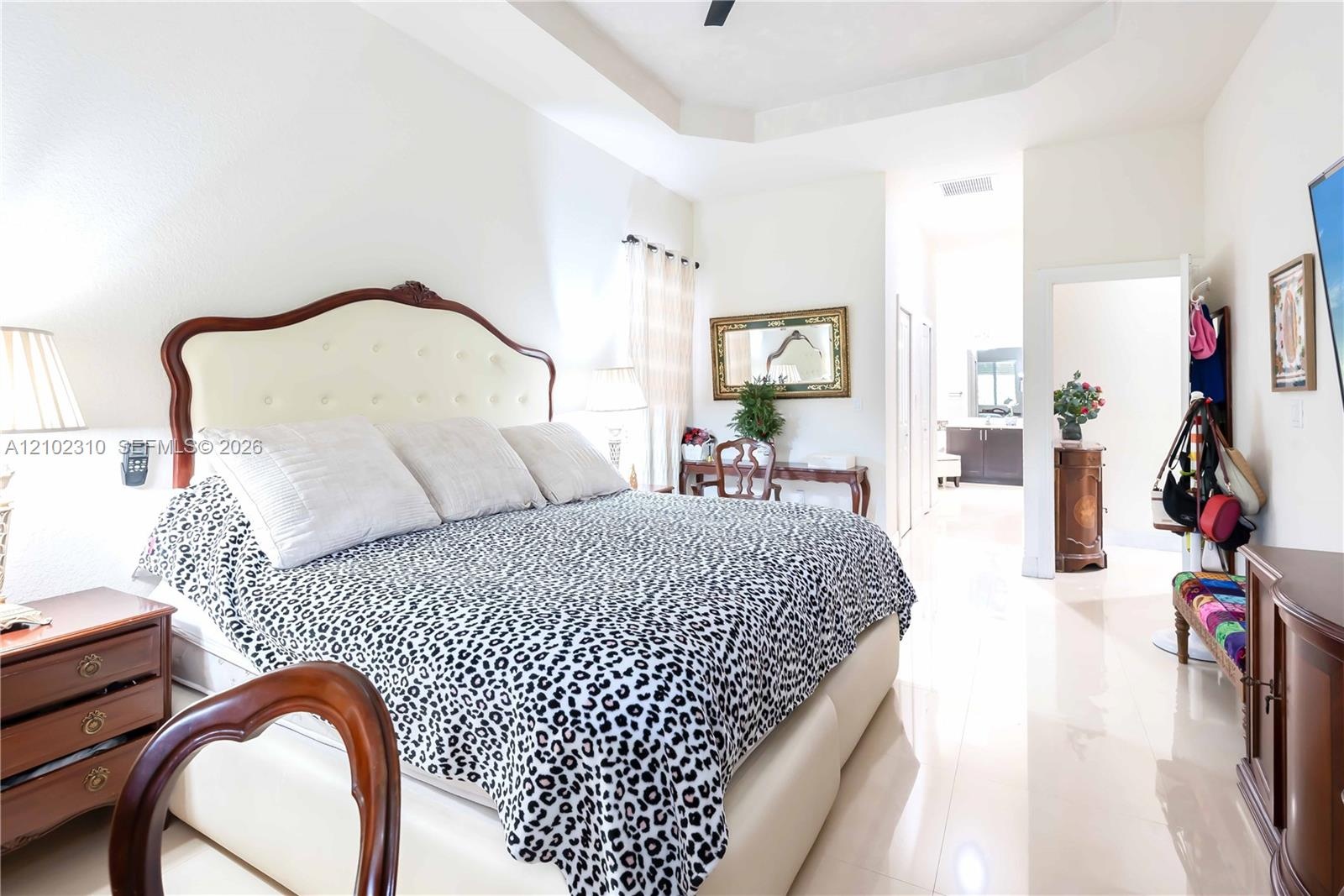 Tray ceiling with integrated fan, polished tile flooring, and neutral wall tones