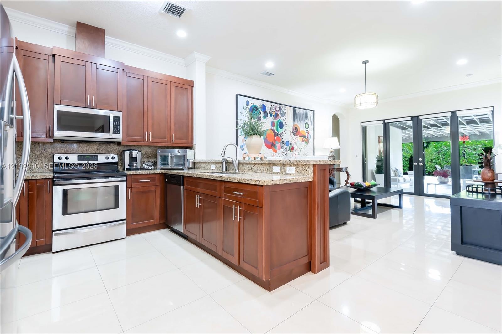 Kitchen featuring dark wood cabinetry, stone-surface countertops, stainless steel appliances, and tile flooring