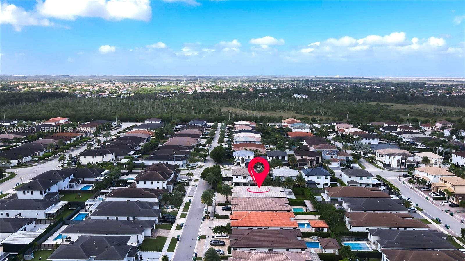 Aerial perspective of a multi-story residence featuring a tile roof, a private swimming pool, and an enclosed rear patio, situated within a master-pla