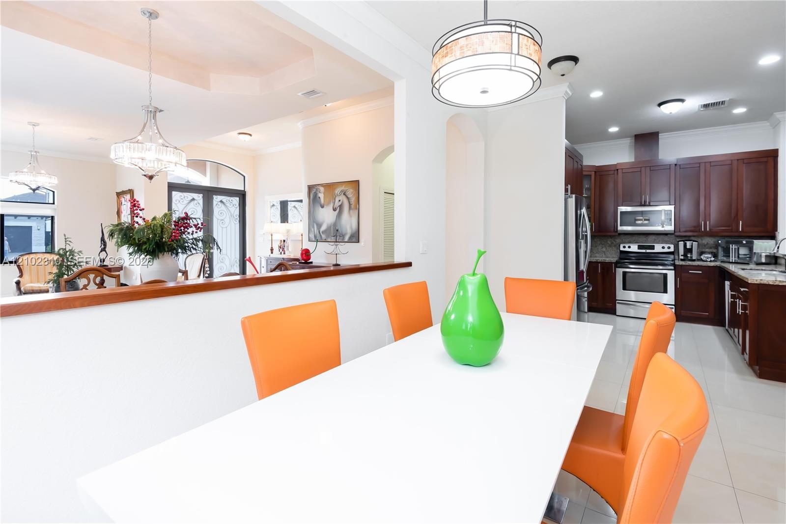 Kitchen featuring dark wood cabinetry, stainless steel appliances, and stone countertops, complemented by recessed lighting and decorative chandeliers
