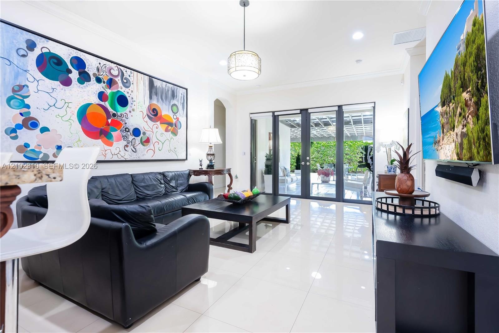 Large-format tile flooring, recessed lighting, crown molding, and floor-to-ceiling glass panel doors with dark frames