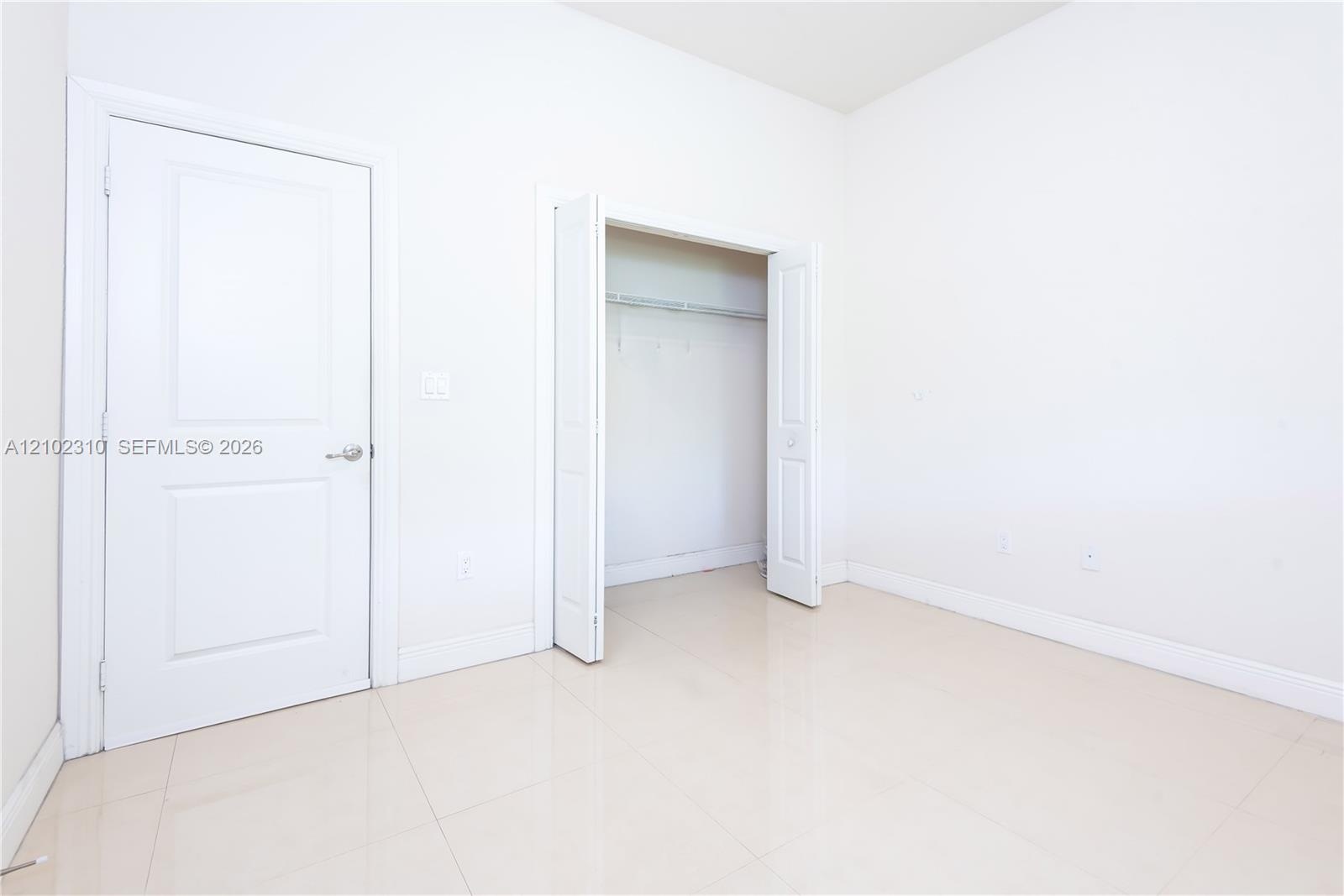 Neutral-toned tile flooring, solid-core interior door, and walk-in closet featuring wire shelving