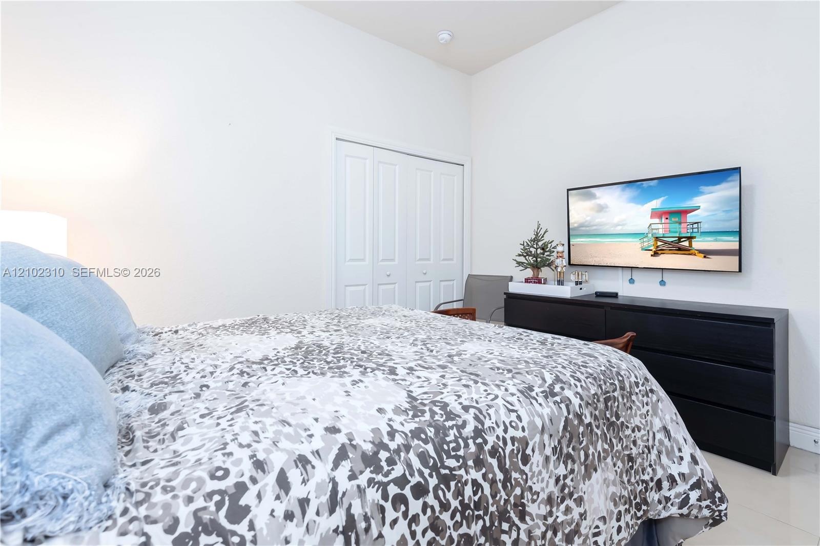 Neutral interior space featuring high ceilings, white wall finishes, tile flooring, and a bi-fold closet