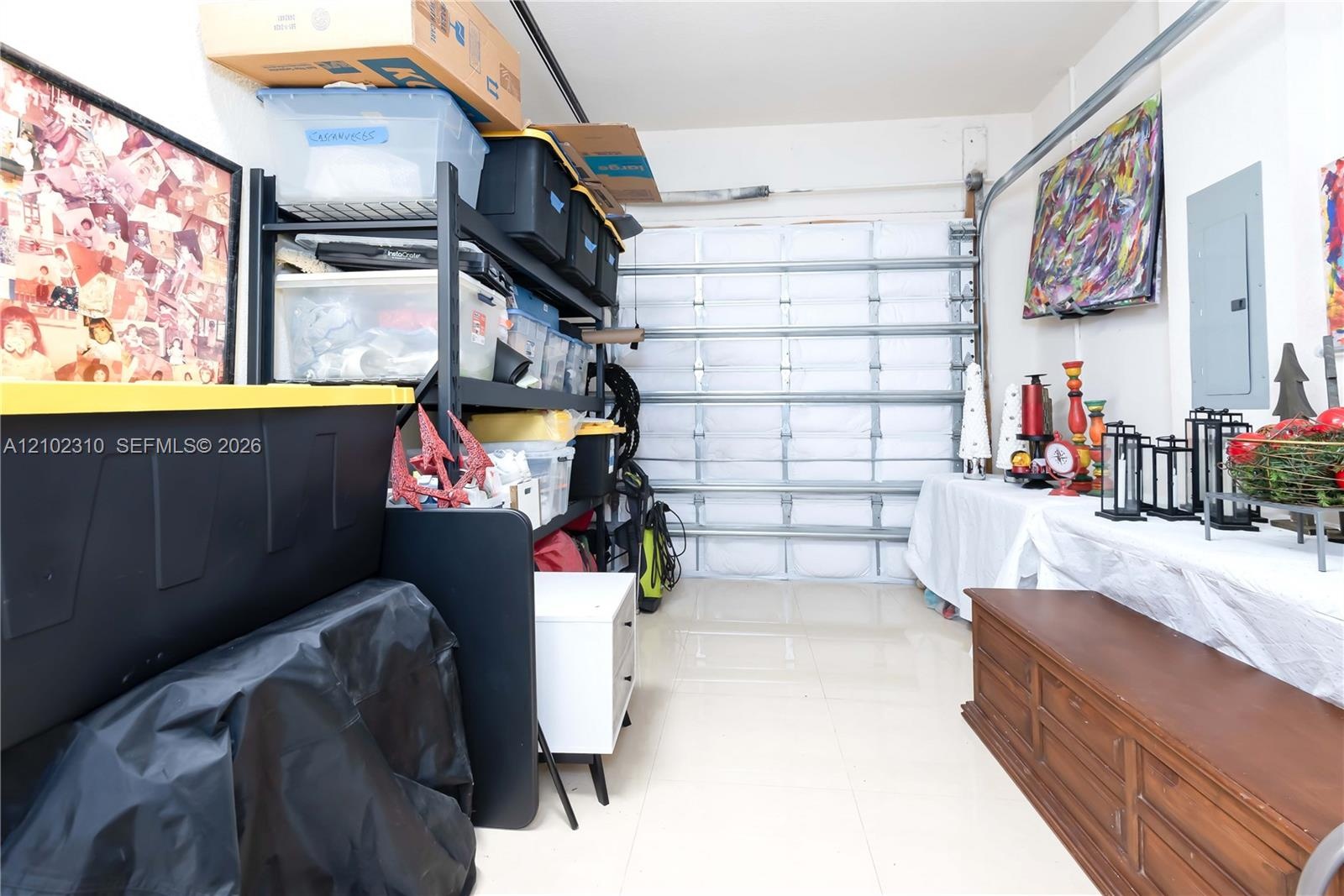 Enclosed garage space featuring a segmented overhead door, smooth-finish flooring, and a wall-mounted electrical panel