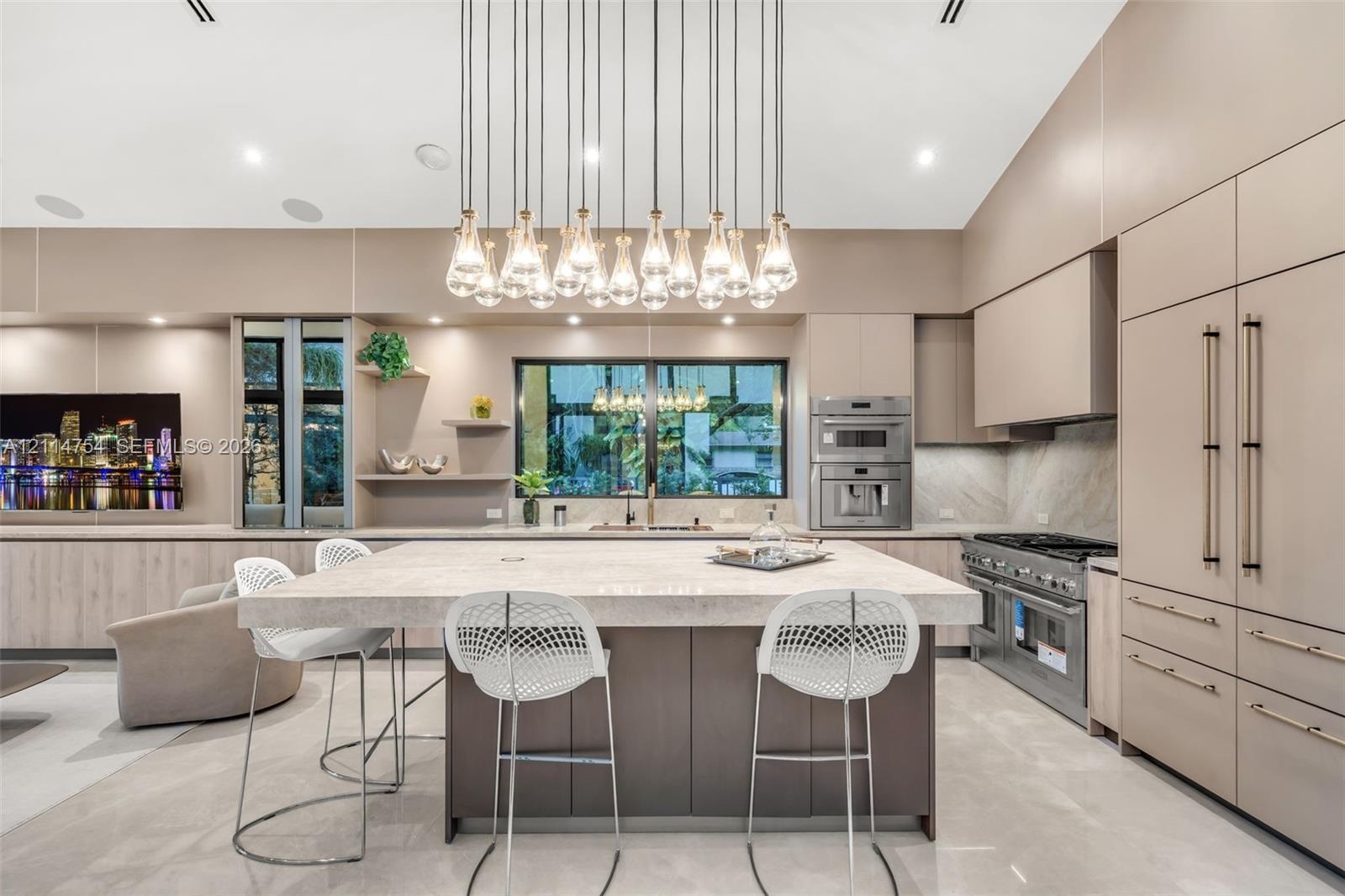 Kitchen featuring flat-panel cabinetry, a large stone-topped central island, built-in stainless steel appliances, and a multi-pendant light fixture be
