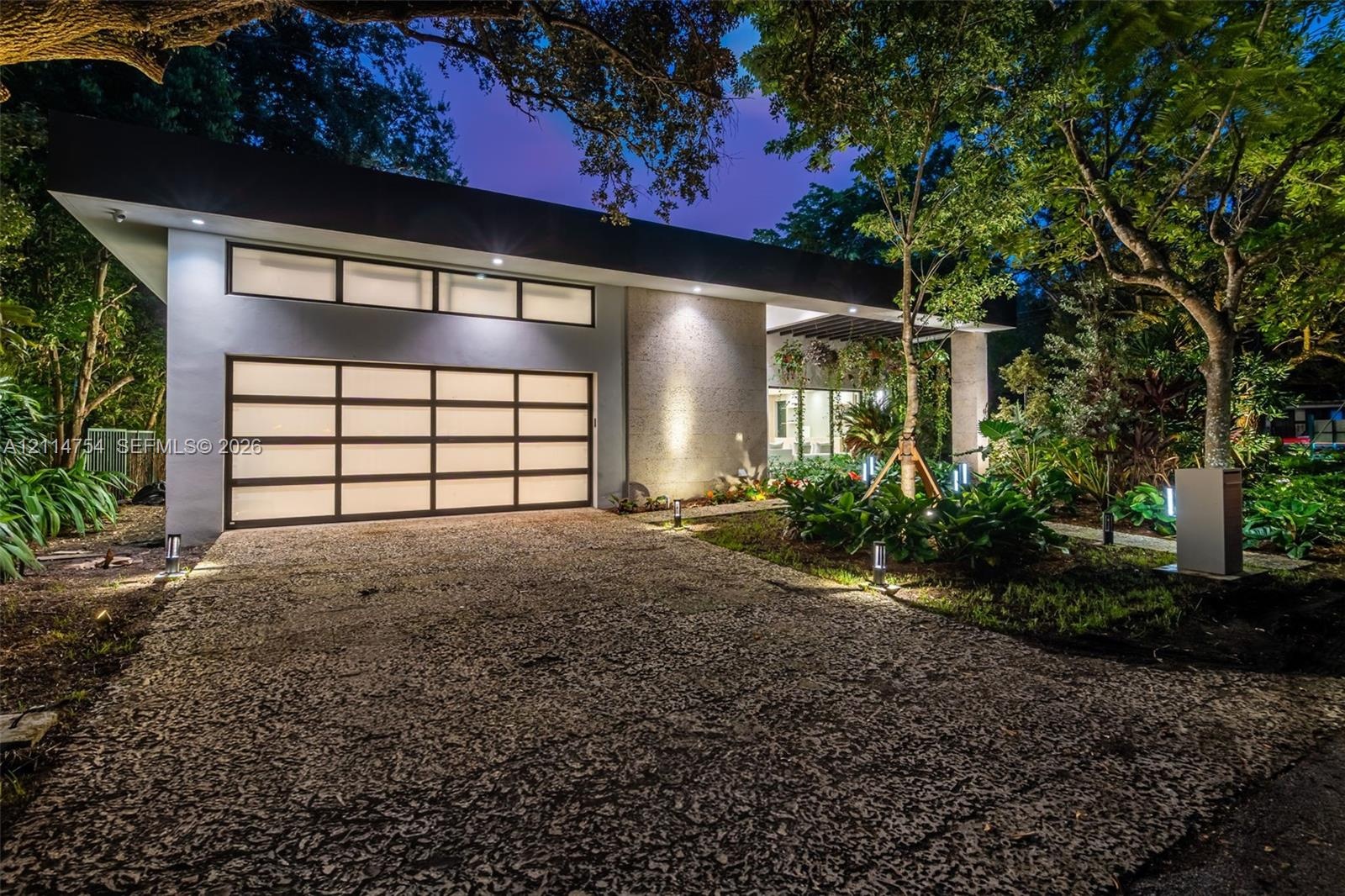 Contemporary exterior featuring a textured stone facade, a multi-pane frosted glass garage door, clerestory windows, and a pergola-covered entry