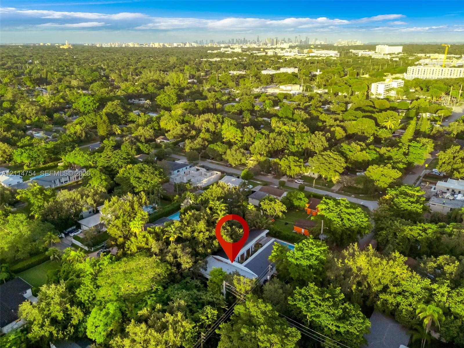 Aerial perspective showcasing a parcel characterized by dense, mature tree canopy, integrated swimming pool, and flat-roof architectural profile withi