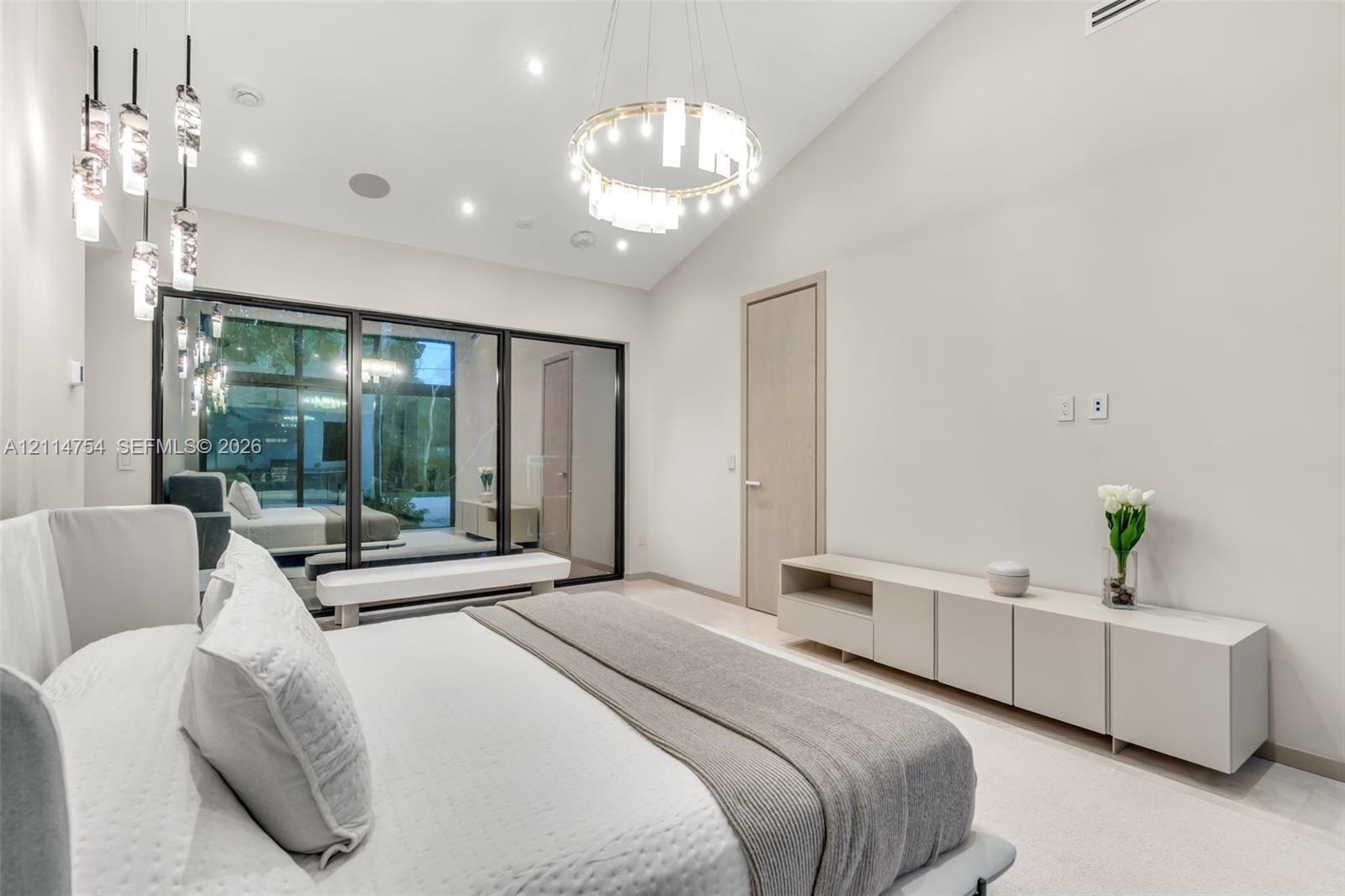 Vaulted ceilings featuring a circular crystal chandelier, recessed lighting, floor-to-ceiling black-framed windows, and built-in matte finish cabinetr