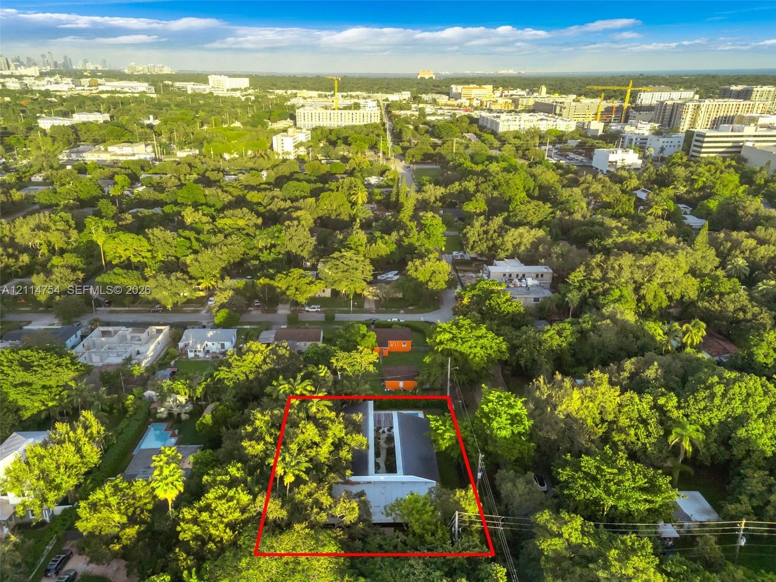 Aerial perspective of property featuring dense mature tree canopy, integrated paved central courtyard, and dark-toned metal roofing
