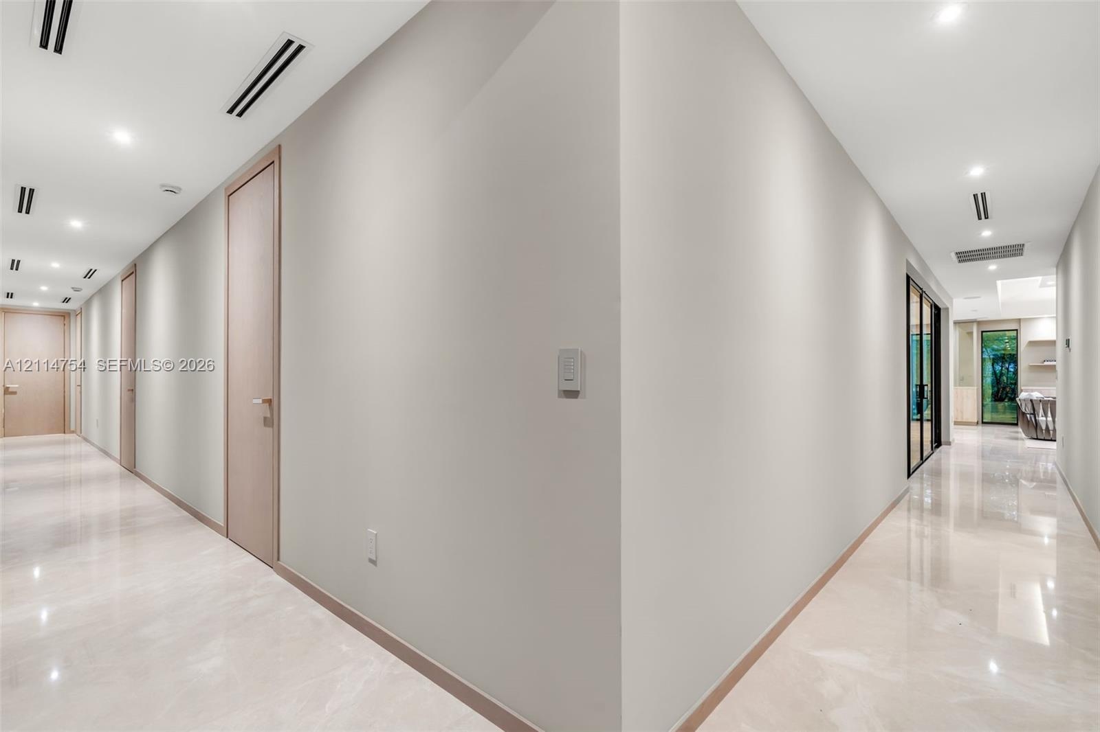 Hallway featuring high-gloss tile flooring, recessed ceiling lighting, linear ceiling diffusers, and wood-finish interior doors