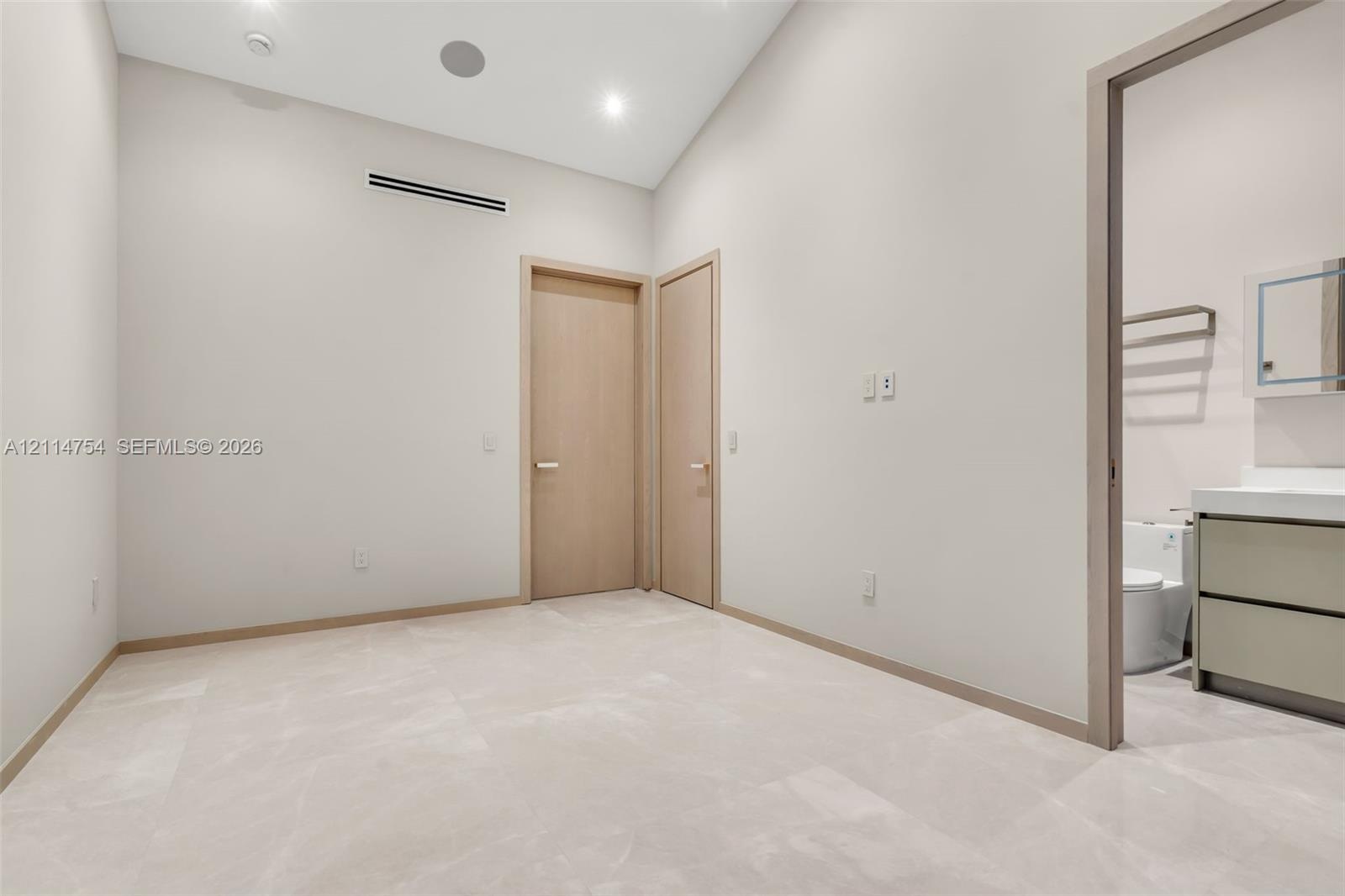 Vaulted ceilings with recessed lighting, stone-finish flooring, and minimalist wood-finish interior doors