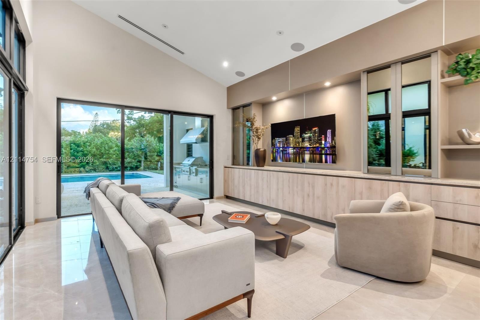 Vaulted ceilings, expansive glass sliding doors, built-in floor-to-ceiling cabinetry, recessed lighting, and large-format tile flooring
