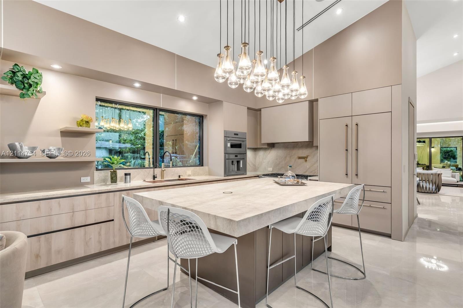 Kitchen featuring a large central island with a thick-profile stone countertop, flat-panel cabinetry, integrated refrigerator, multi-tiered pendant li