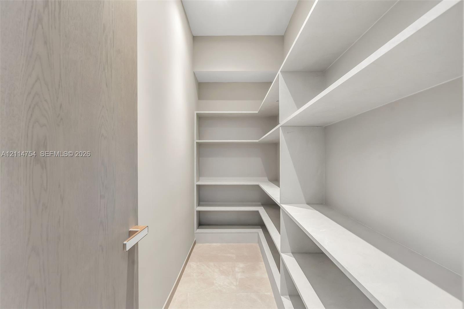 Storage area featuring custom white shelving, wood-finish door, and metal door hardware