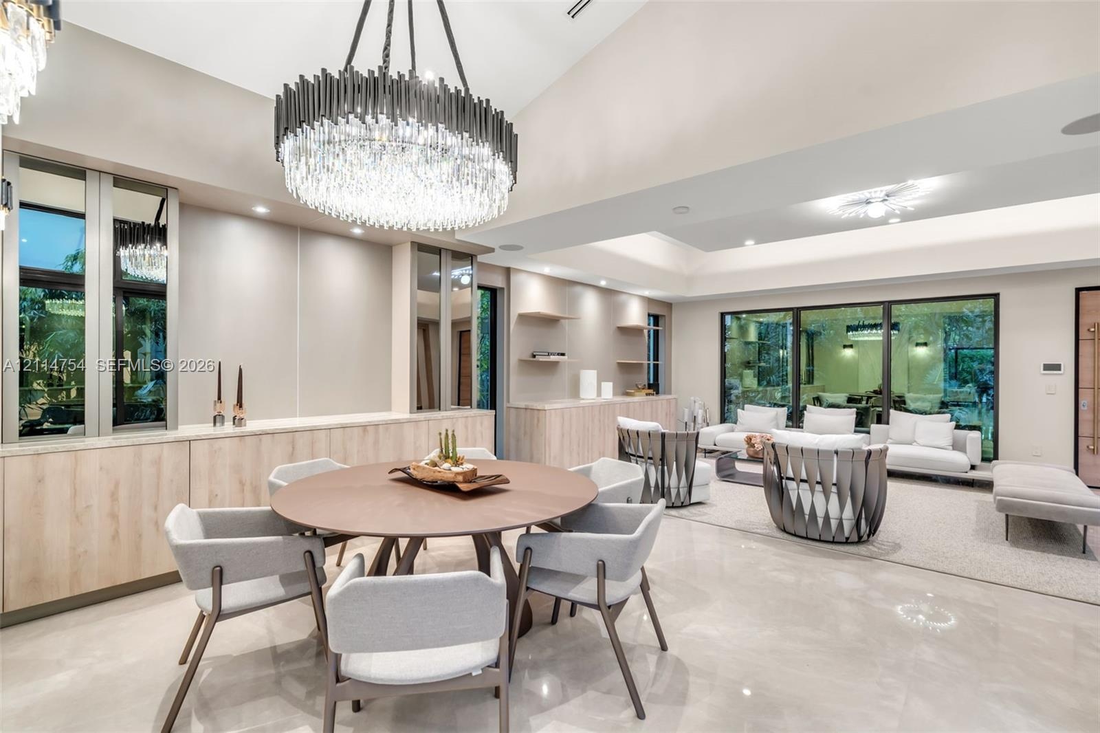 Vaulted ceilings, large-scale crystal chandelier, built-in cabinetry with light wood finish, stone-finish flooring, and floor-to-ceiling glass wall pa