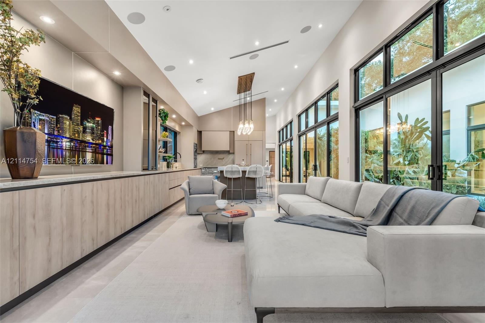 Vaulted ceilings with recessed lighting, floor-to-ceiling multi-panel glass doors, custom wall-to-wall cabinetry with stone countertops, and integrate