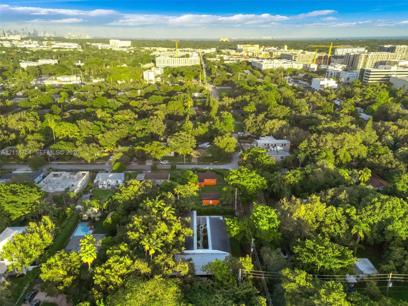 Aerial perspective of a detached residential property featuring a flat roofline, central skylight structure, and a backyard swimming pool, set within 