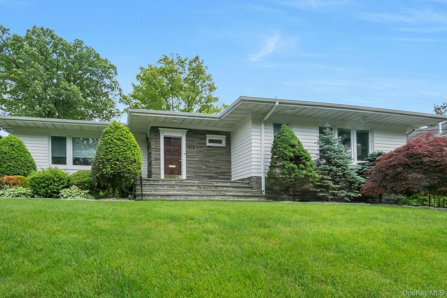 View of front facade featuring a front yard and stone siding