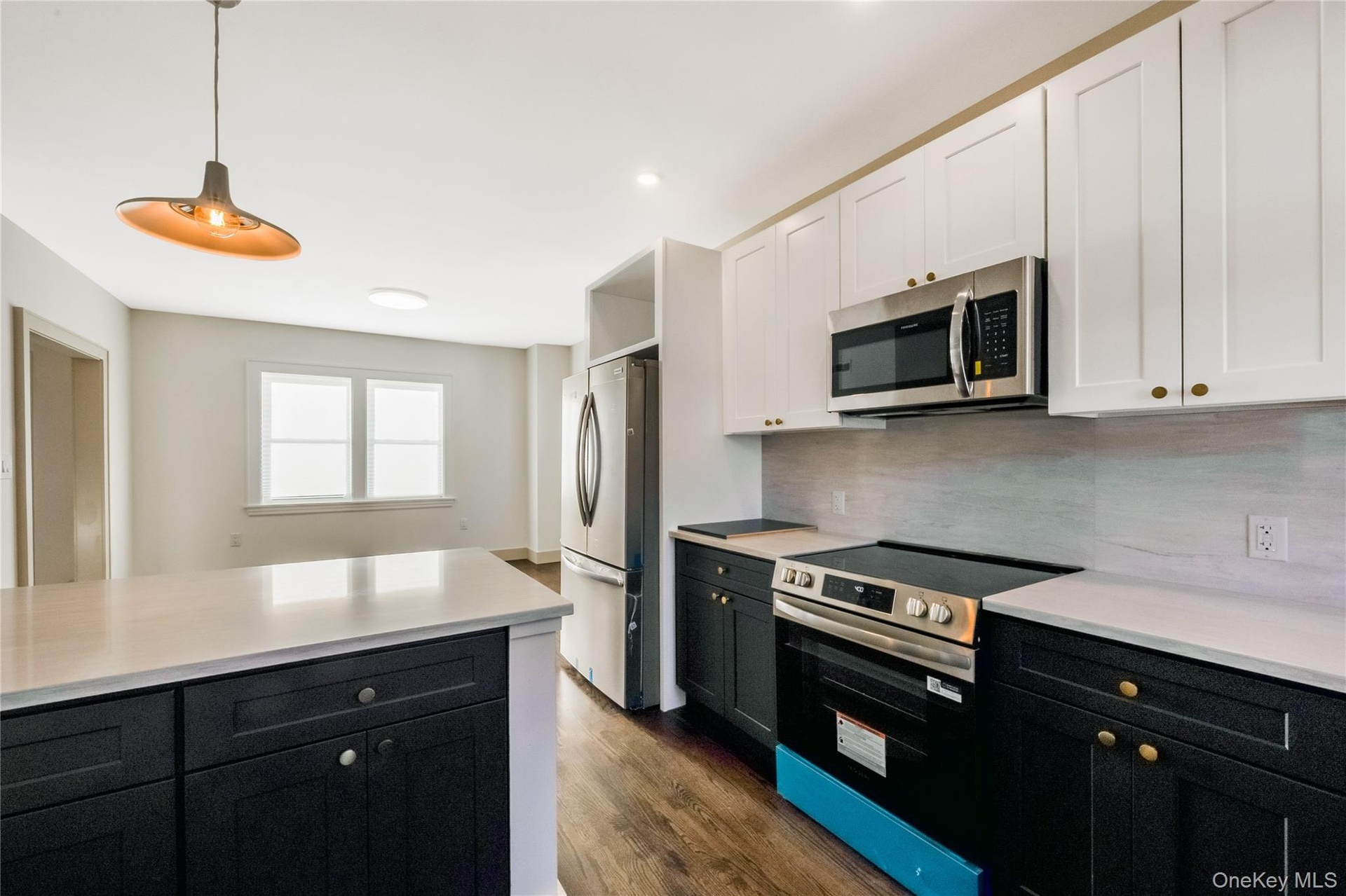 Eat in Kitchen featuring two-tone navy and white shaker cabinetry, quartz countertops, stainless steel appliances, a center island, and wood-finish fl