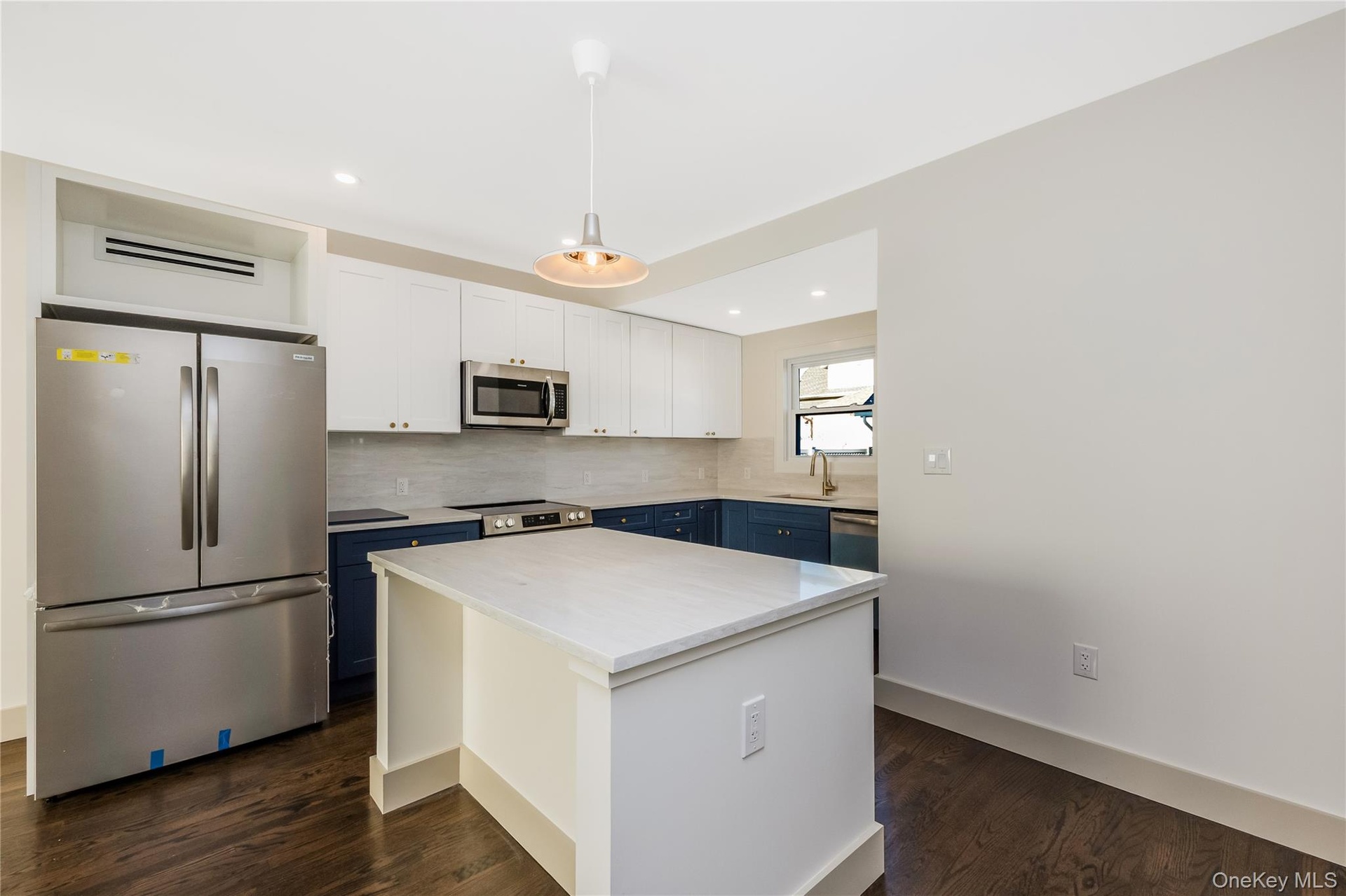 Eat in kitchen featuring two-tone navy and white shaker cabinetry, quartz countertops, stainless steel appliances, a center island, and wood-finish fl