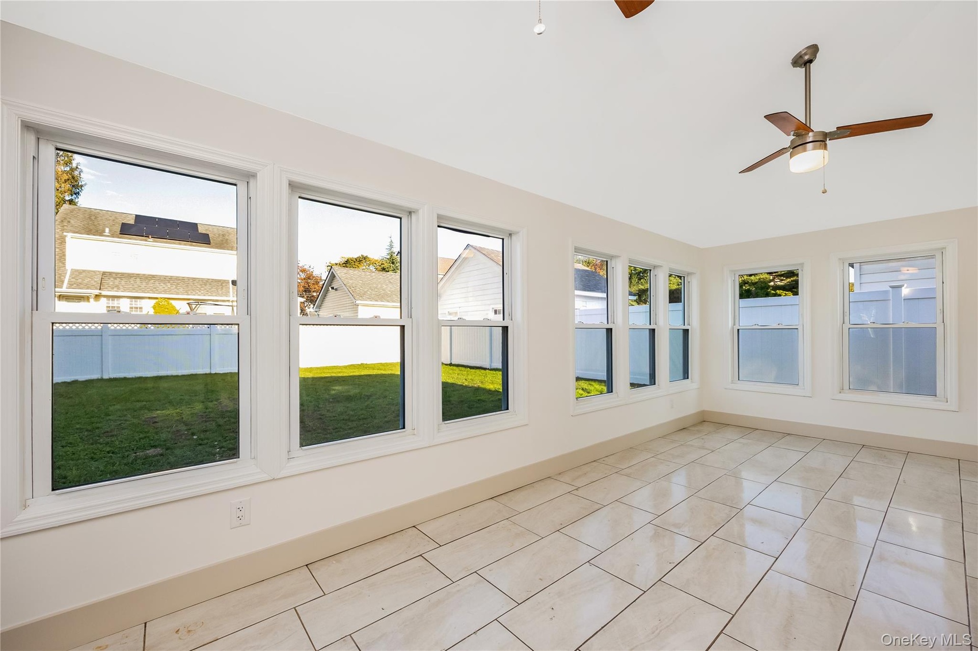 All seasons room surrounded by oversized windows, ceramic tile flooring, and a ceiling fan
