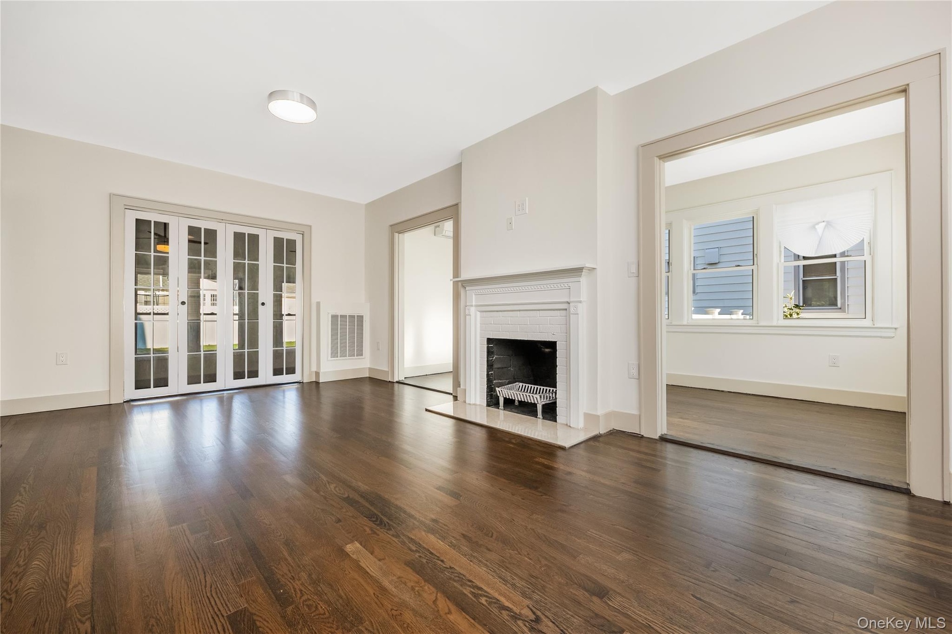 Wood flooring, fireplace with a decorative mantel, multi-pane glass doors, and window-lined interior space
