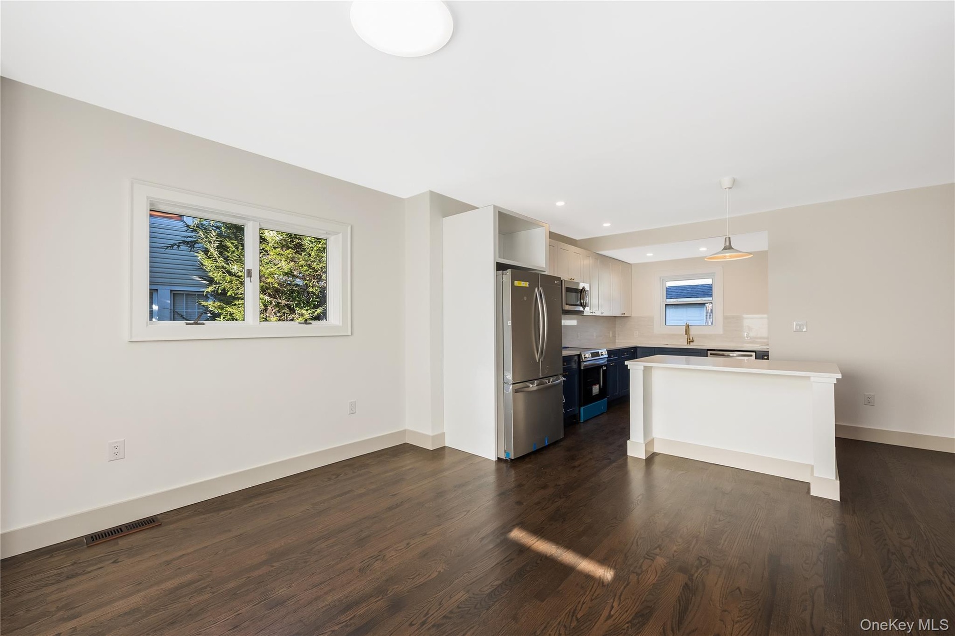 Eat in kitchen leading into the Dining room featuring two-tone navy and white shaker cabinetry, quartz countertops, stainless steel appliances, a cent