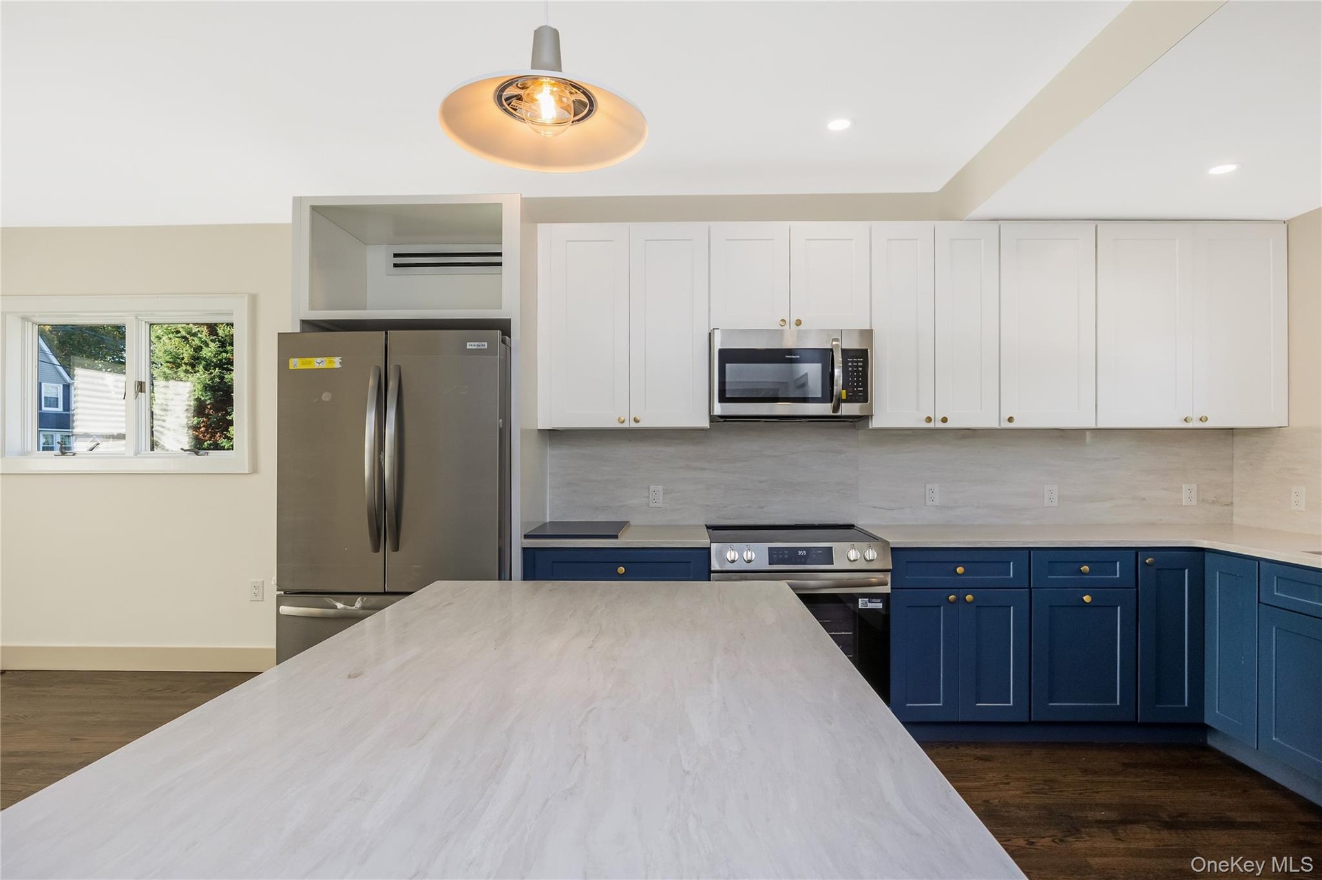 Eat in kitchen featuring two-tone navy and white shaker cabinetry, quartz countertops, stainless steel appliances, a center island, and wood-finish fl
