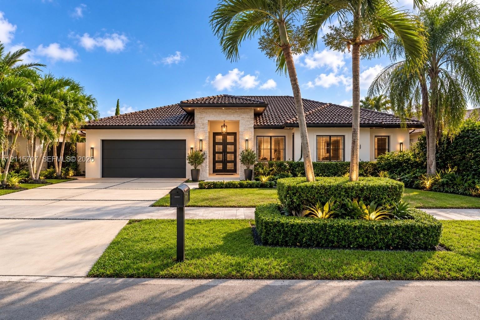 Single-story exterior featuring a tile roof, stone masonry facade, multi-panel glass entry door, and paved driveway