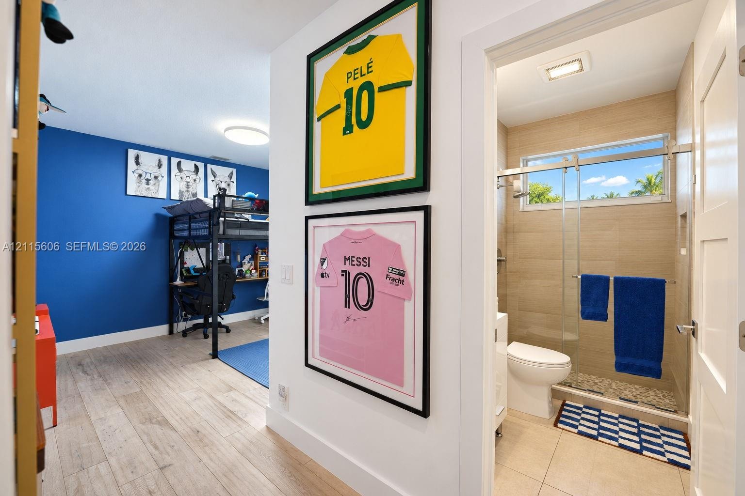 Wood-finish flooring throughout, bathroom featuring beige wall tile, a glass-enclosed shower with a stone-finish floor, and a rectangular horizontal w
