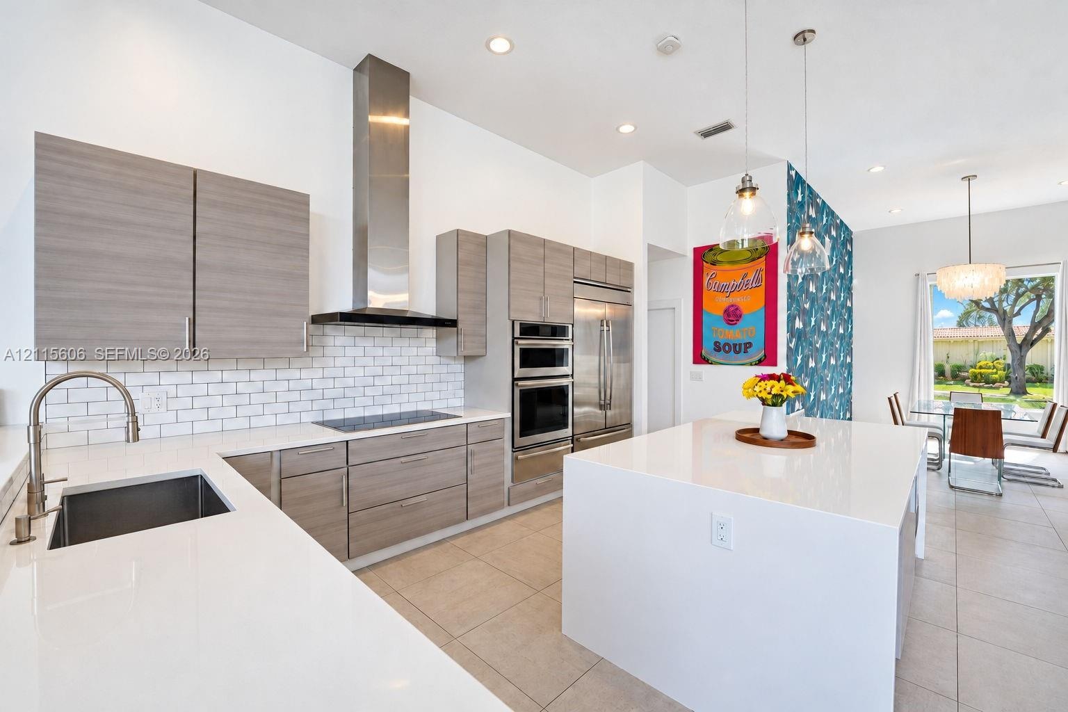 Kitchen featuring flat-panel wood-finish cabinetry, white countertops, a stainless steel chimney-style range hood, subway tile backsplash, and a large