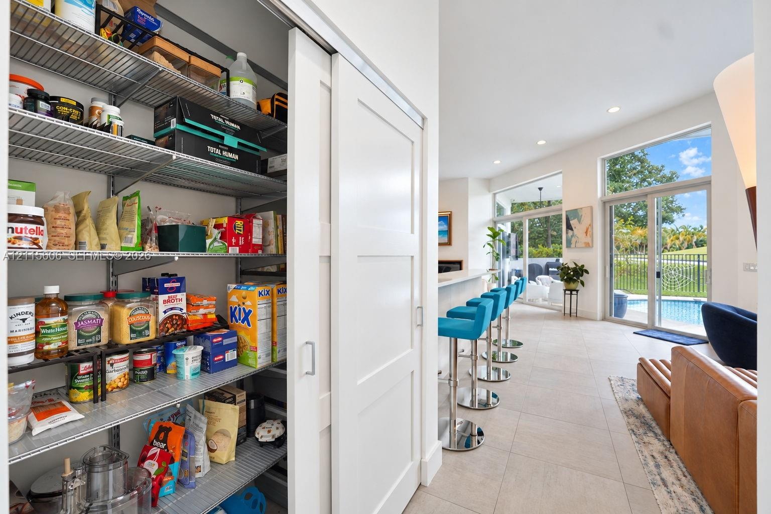 Walk-in pantry featuring adjustable wire shelving and a sliding shaker-style door, highlighted by neutral tile flooring, recessed lighting, and expans