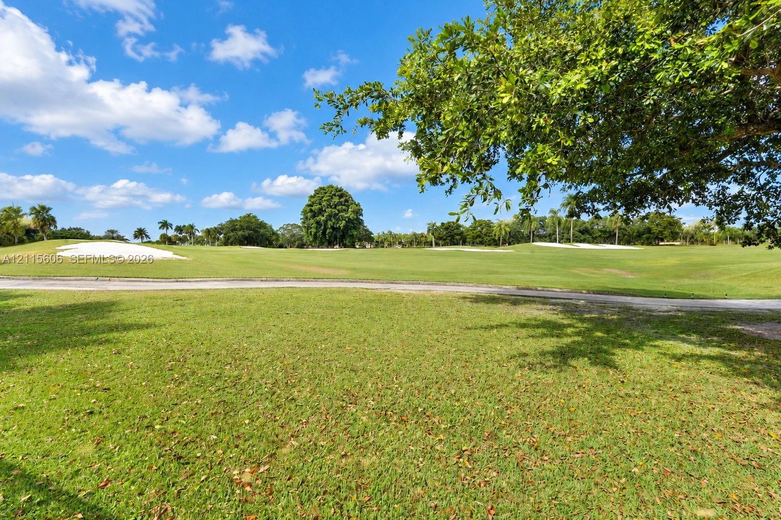 Expansive green space featuring golf course fairways, sand bunkers, paved cart paths, and mature landscaping